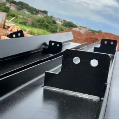 Vigas metálicas pretas com chapas de ligação soldadas, no canteiro de obra