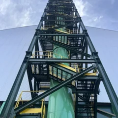 Torre metálica com escadas e guarda-corpos amarelos, vista de baixo