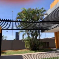Pergolado metálico com brises sobre área externa com palmeiras